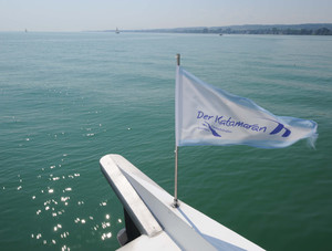 Fahne des Katamarans im Wind mit Blick auf den Bodensee